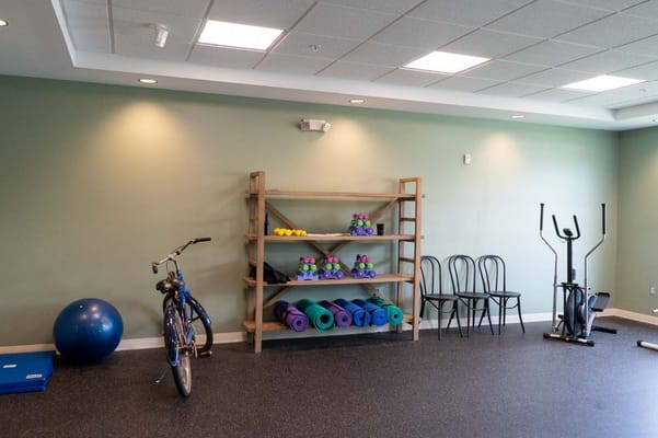 Well-equipped fitness room with exercise equipment and yoga mats