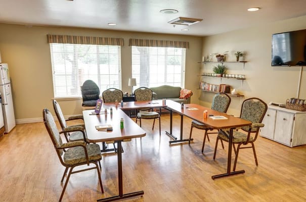 Bright common area with tables and chairs set up for activities