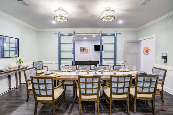 Spacious dining room set with a long table and decorative chairs.