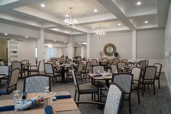 Dining room with tables and chairs arranged for residents