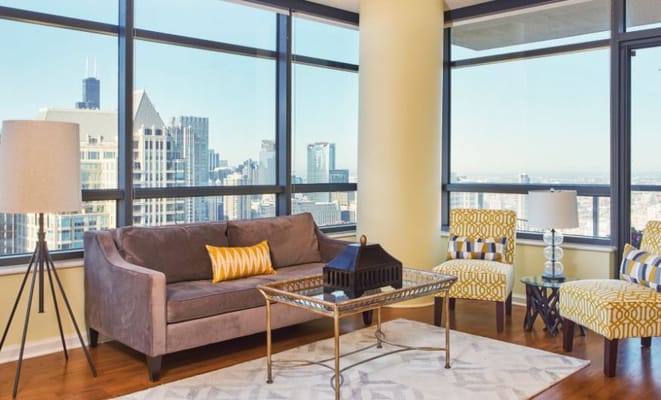 Modern living room featuring a sofa and yellow accent chairs with city skyline view