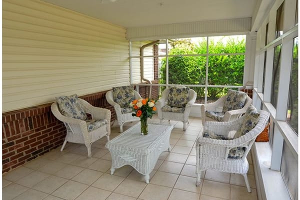 Cozy sunroom with white wicker chairs and floral cushions