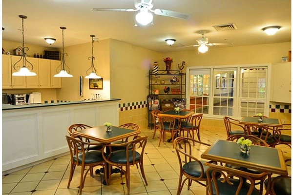 Cozy dining area with wooden tables and chairs, featuring flowers on each table