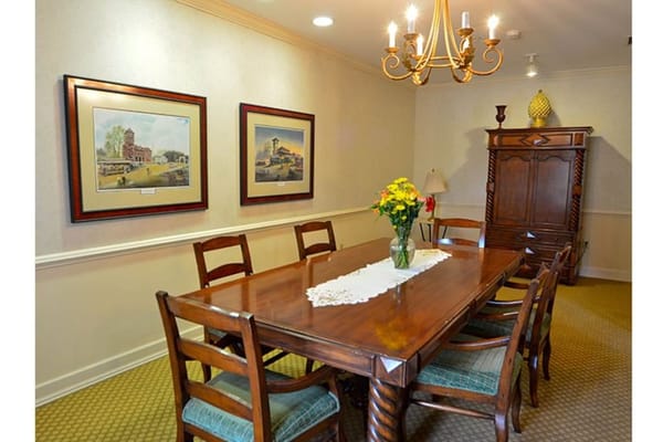A dining room with a wooden table, chairs, and artwork on the walls.