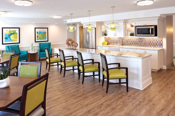 A bright and modern kitchen area in a senior living facility with colorful seating.
