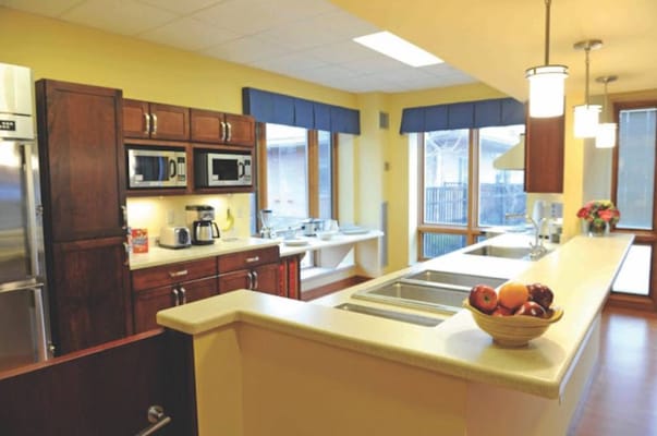 A spacious kitchen with modern appliances and a bowl of fruit on the counter.