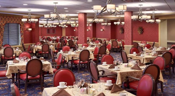 Spacious dining room with red decor and round tables set for meals