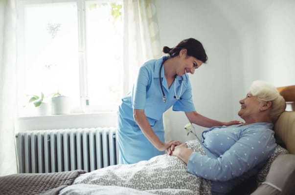 Nurse interacting with a senior resident in a bedroom