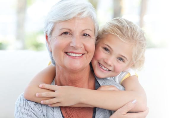 Senior woman with a young girl embracing and smiling