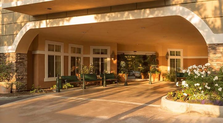 Entrance of Atria Grand Oaks with flowers and seating area