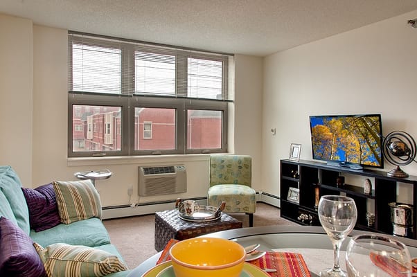 Bright living room with blue couch, green chair, and TV