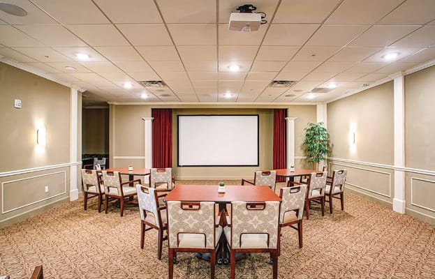 Quiet auditorium with chairs arranged around a central table and a large projection screen.