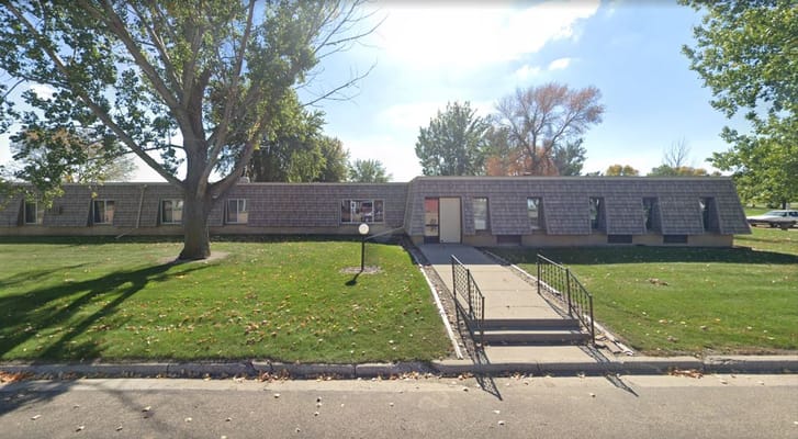 Front exterior of Dakota Estates Retirement Center showing landscaping and entrance.