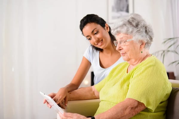 Caregiver assisting a senior resident with a tablet