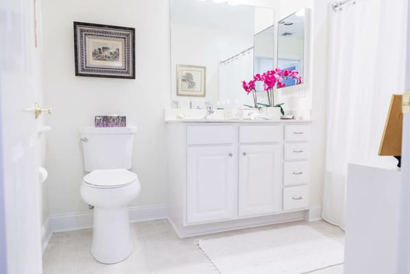 Bright, clean bathroom with a sink, mirror, and toilet