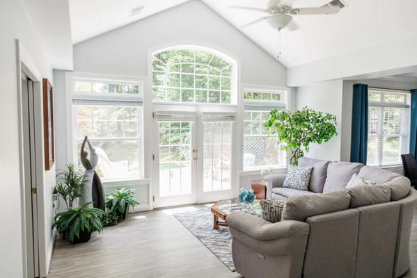 Bright sunroom featuring comfortable seating and greenery