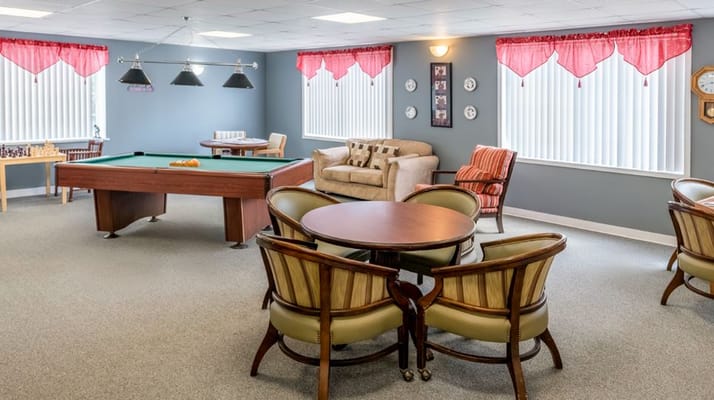 Bright and inviting activity room with a pool table and seating area.