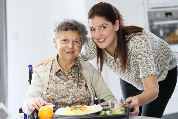 Caregiver and resident smiling over a meal