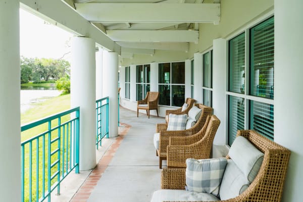 Comfortable seating on a covered porch overlooking a green area.