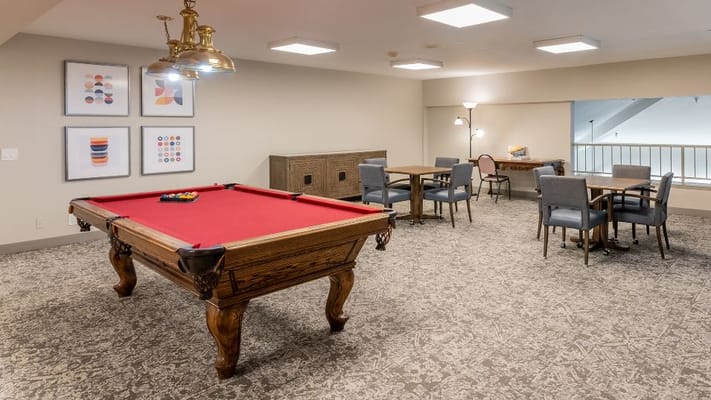 Billiards table in a recreational area with tables and chairs