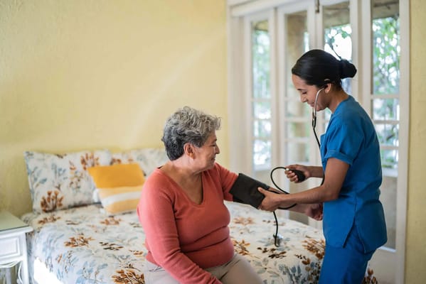 Nurse taking blood pressure of a resident in a cozy room