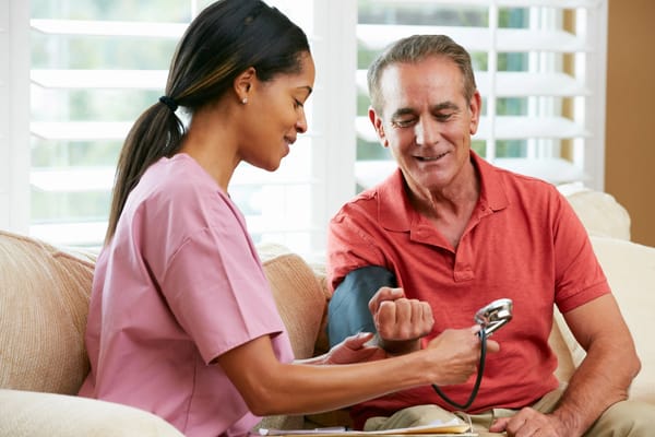 Nurse taking a patient's blood pressure in a living room