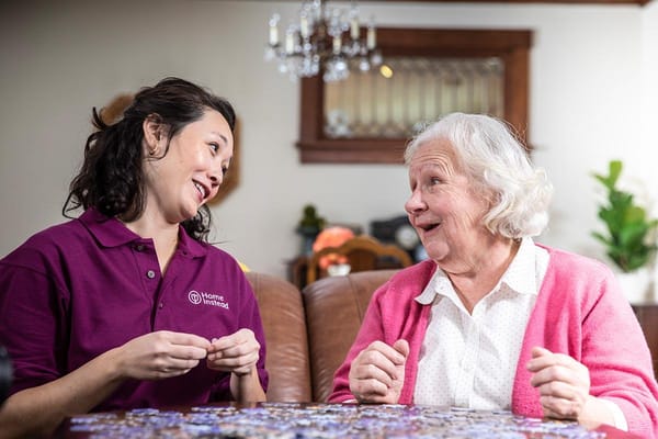 A caregiver conversing with a resident during a puzzle activity.