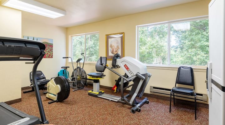 A fitness room with exercise equipment and large windows