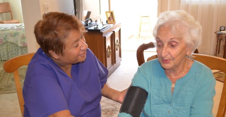 A caregiver taking blood pressure of an elderly resident