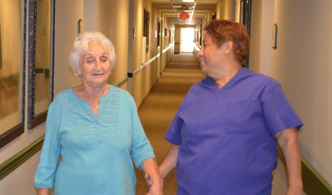 Caregiver walking with a resident in a hallway