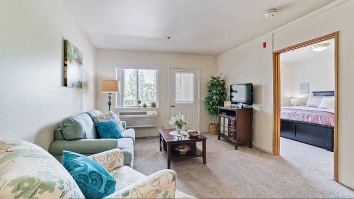 A cozy living room with a couch, coffee table, and TV at Mission Commons.