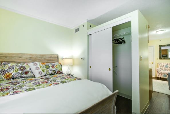 A well-decorated bedroom with colorful bedding and a closet.