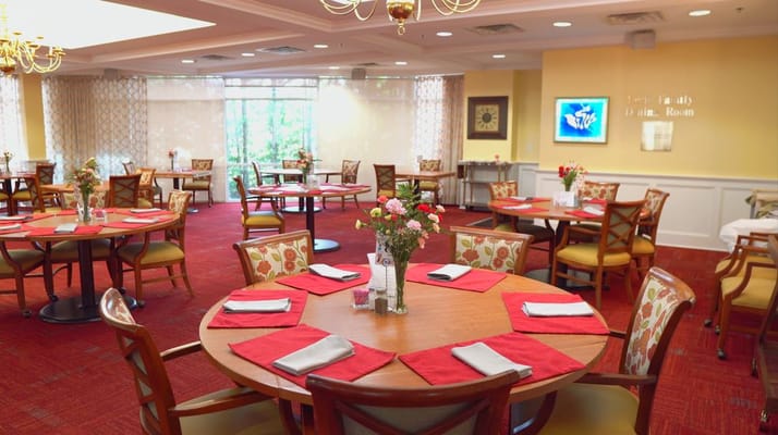 Brightly lit dining room with round tables and floral centerpieces