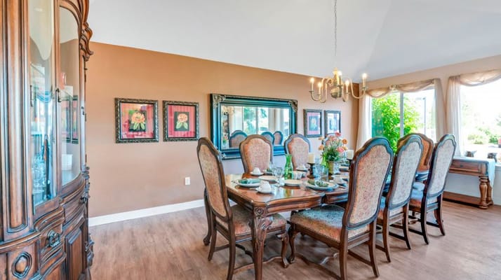 Dining area with a large table set for a meal, featuring elegant chairs and decorations.