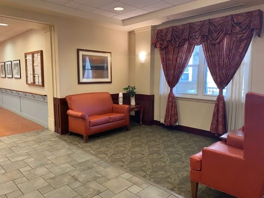 Lounge seating area with orange sofas and decorative curtains.