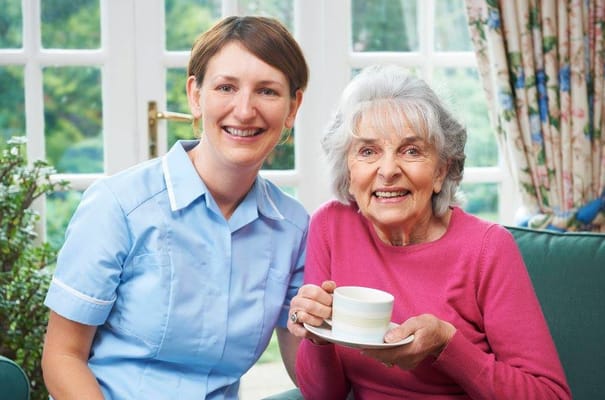A caregiver and resident smiling together in a living space
