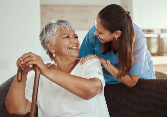 A staff member assisting a smiling resident in a common area