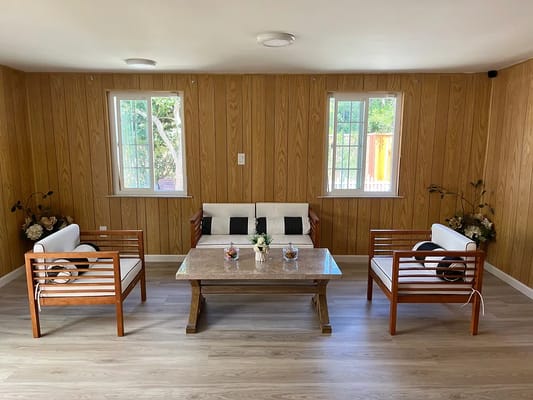 A cozy living room with wooden walls, a table, and seating.