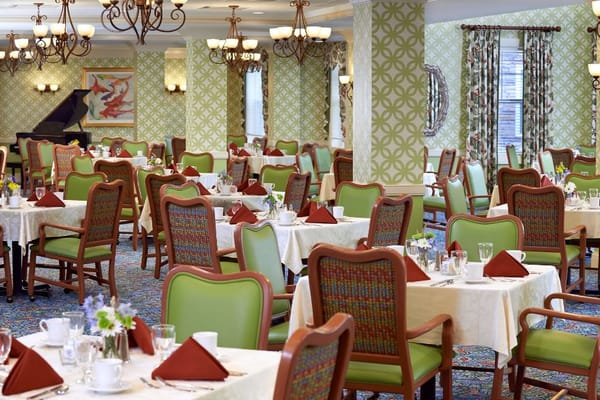 Brightly decorated dining room with green chairs and white tables