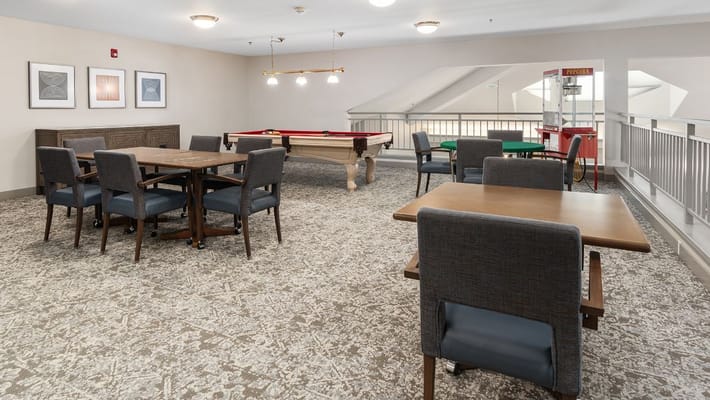 Interior of the game room featuring a pool table, tables, and seating.