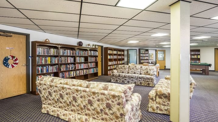 A spacious library lounge with floral couches and bookshelves.