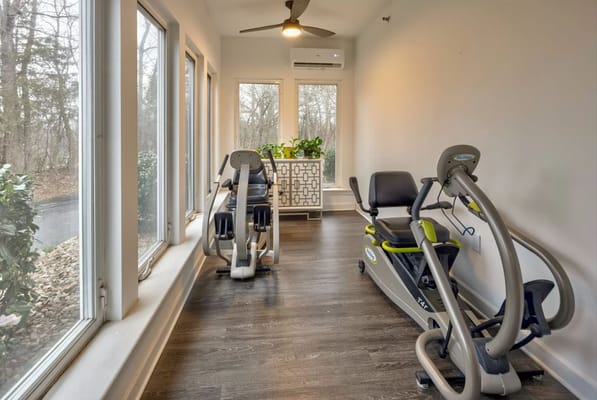 Well-lit gym with exercise equipment and large windows