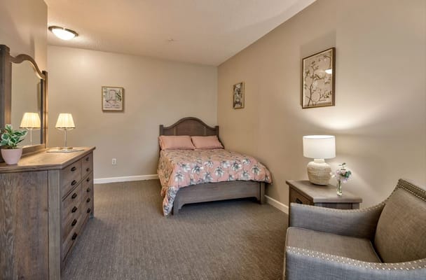 A cozy bedroom with a double bed, dresser, and chair.