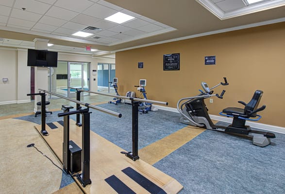 Therapy gym featuring exercise equipment and parallel bars