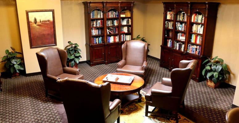 A reading room with comfortable chairs and bookshelves in Villa Fontana.