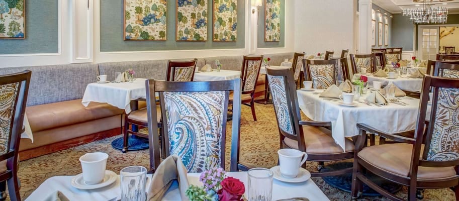 Dining room with tables set for meals and floral decor