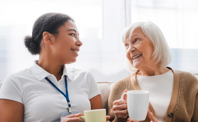 Caregiver and resident enjoying conversation with cups