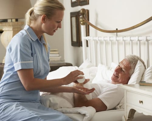 Nurse assisting a senior resident in a bedroom