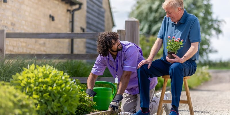 Caregiver and resident gardening together outside