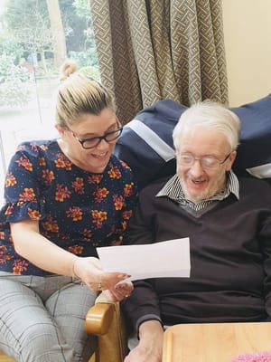 An employee and resident smiling while looking at a paper